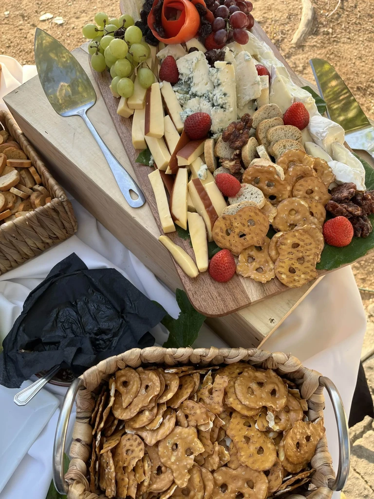 Abundant outdoor charcuterie board with cheeses, fruits, and snacks.