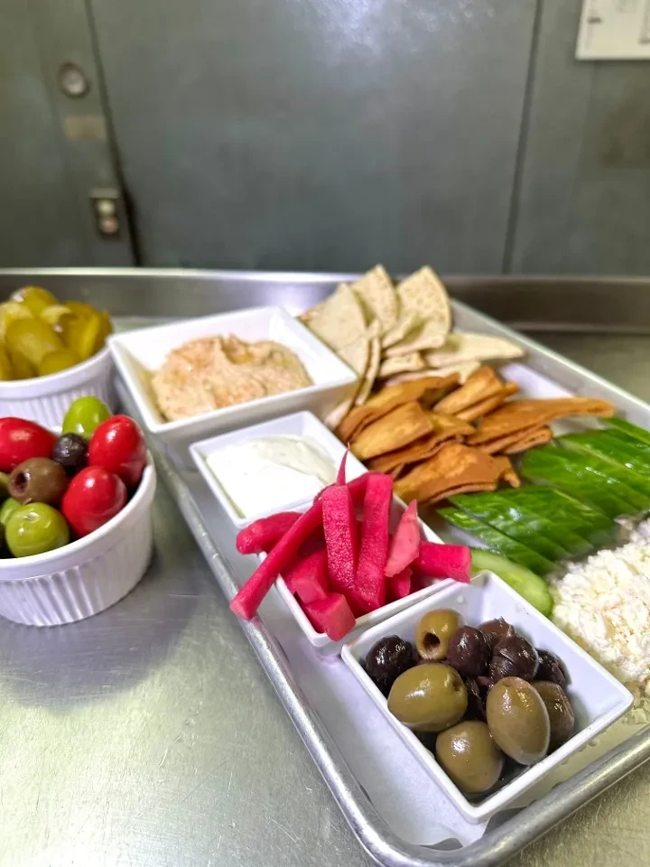 A large silver tray filled with diverse Mediterranean appetizers and dips.