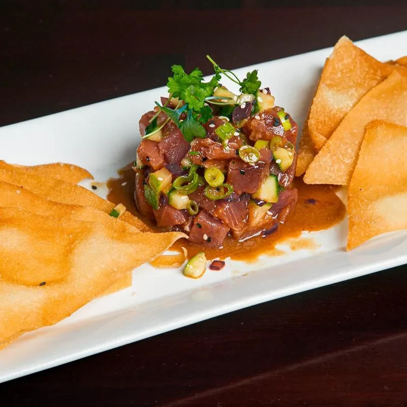 Tuna poke with green ingredients, brown sauce, and wonton crackers.