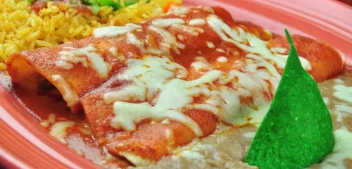 Red enchiladas with melted cheese, yellow rice, refried beans, a green tortilla chip.