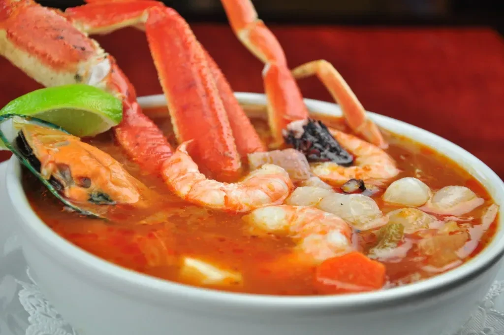 Close-up of vibrant seafood soup with crab legs, shrimp, and mussel.