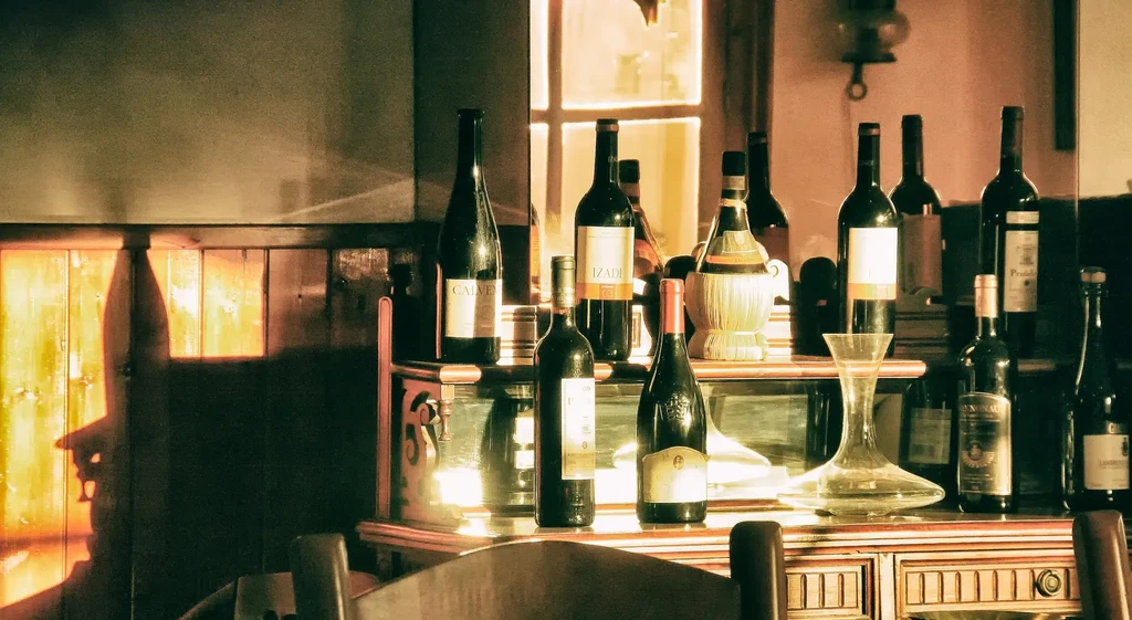 Warmly lit rustic display of various wine bottles and a decanter.