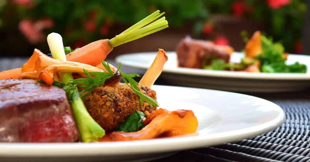 Artfully plated gourmet meal with meat, vegetables, and chanterelle mushrooms.