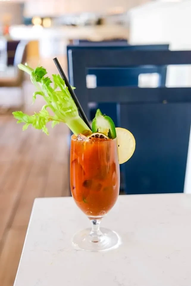 Elaborately garnished Bloody Mary cocktail in stemmed glass on marble.