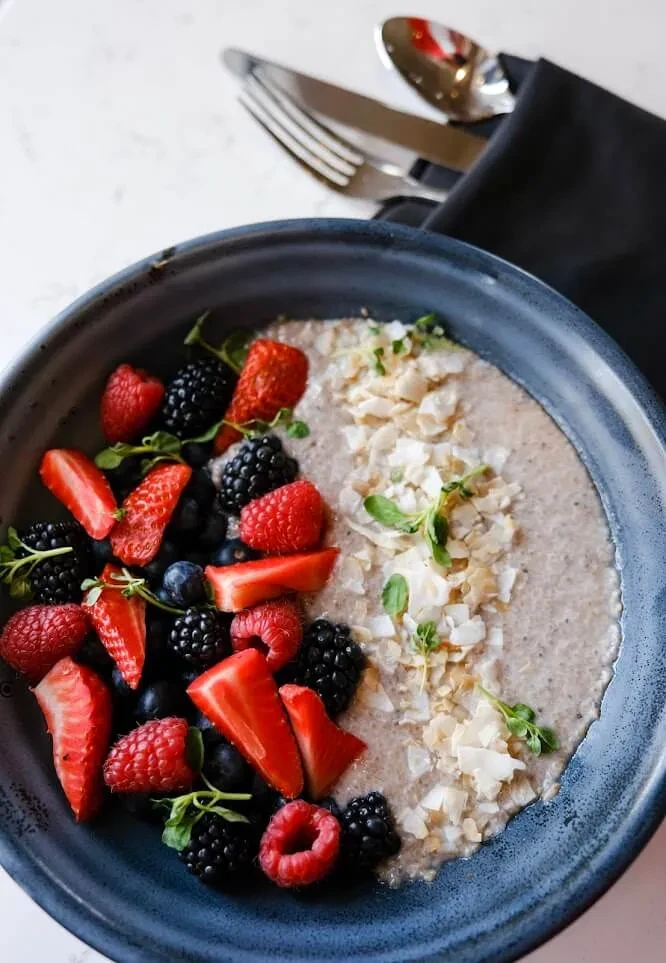 Overhead shot: creamy berry bowl with coconut chips and mint.