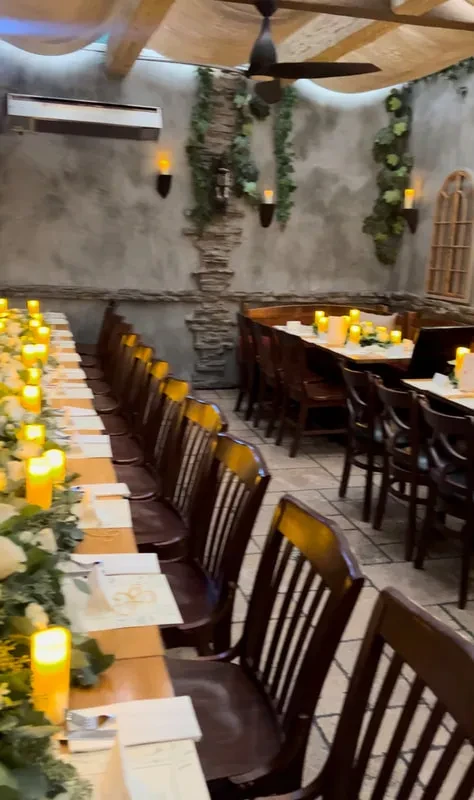 Rustic elegant venue with long dining tables decorated with candles and greenery.