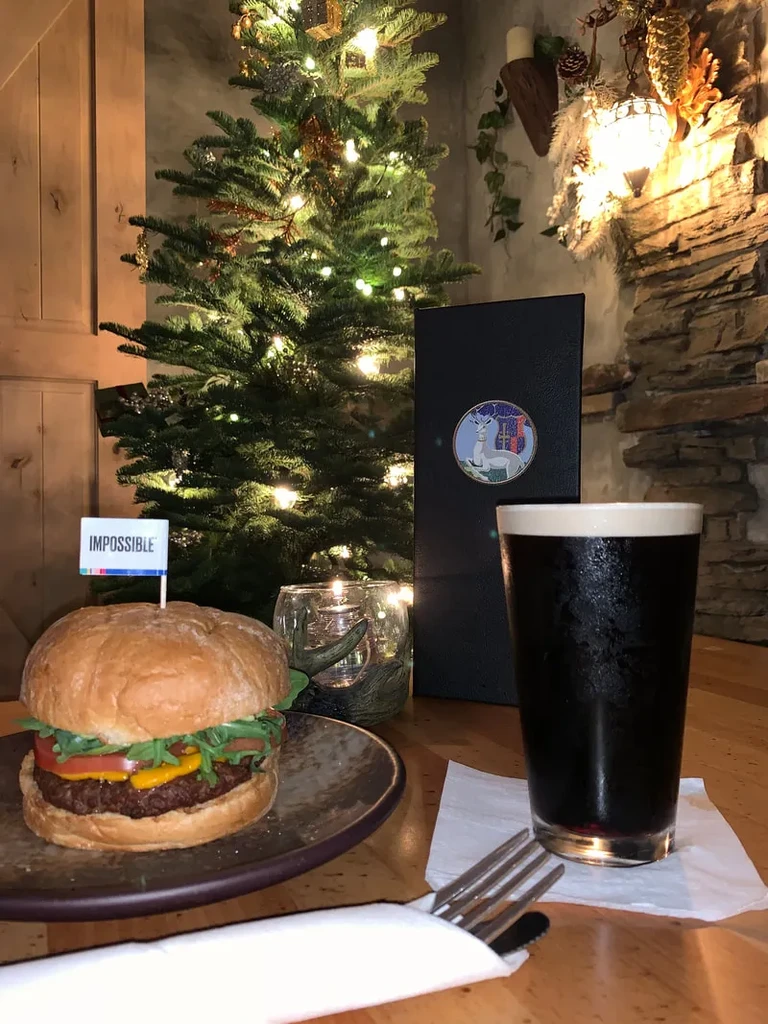Impossible Burger, dark beer, and Christmas tree in a cozy restaurant.
