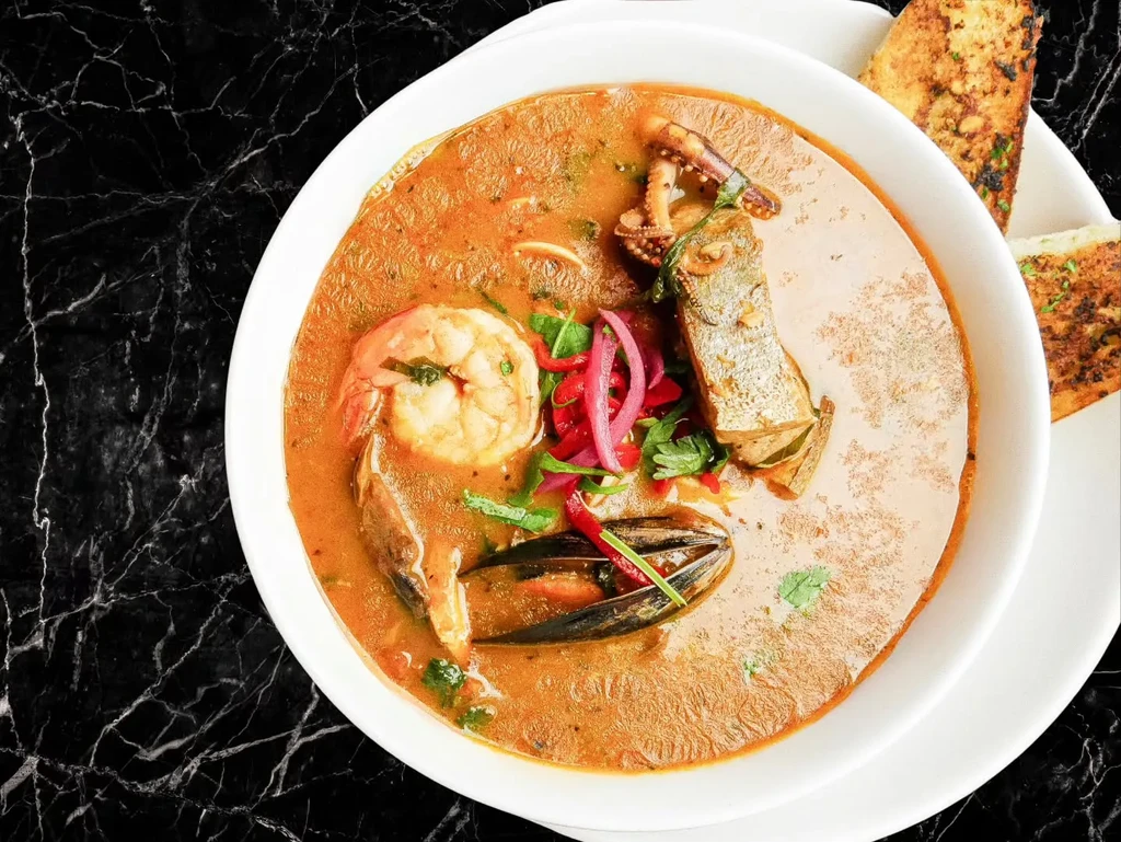 Vibrant seafood stew with shrimp, mussels, fish, and toasted bread.