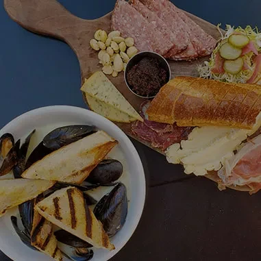 Charcuterie board with meats and cheeses, alongside steamed mussels.