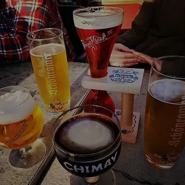 Five distinct beers in branded glasses on a table, one elevated.