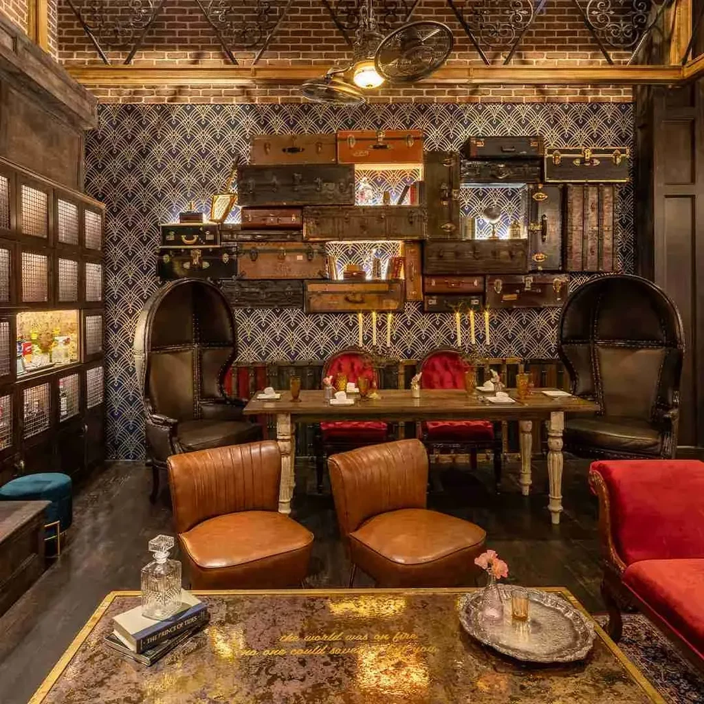 Vintage lounge with antique suitcases, red velvet chairs, and cozy lighting.