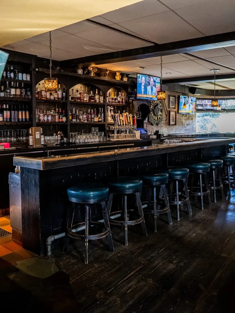 McLLDOON'S Irish Pub interior: long wooden bar, stools, liquor shelf, TVs.