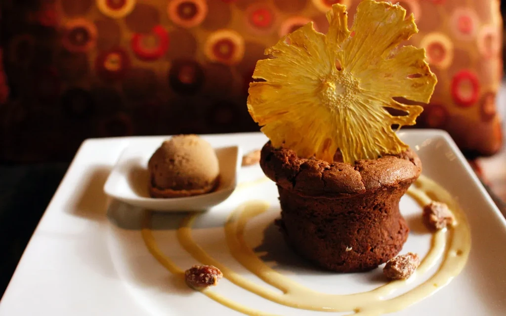 Rustic chocolate dessert, dried pineapple, ice cream, sauce, and candied nuts.