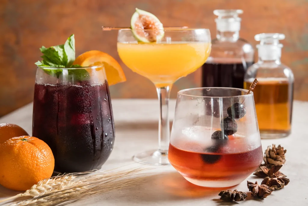 Three garnished cocktails displayed with natural elements.