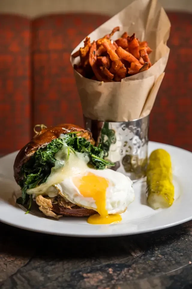Pulled meat burger with fried egg, sweet potato fries, and pickle.