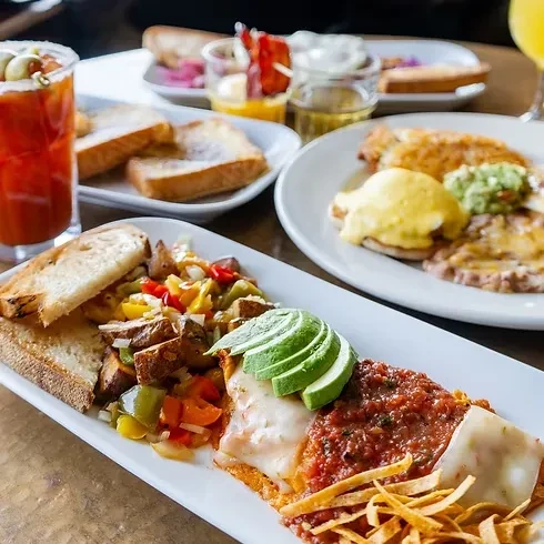 Vibrant spread of various breakfast and brunch dishes on a wooden table.