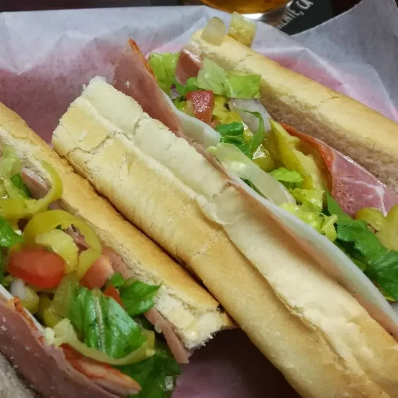 Close-up: Two colorful submarine sandwiches with meat, cheese, and vegetables.