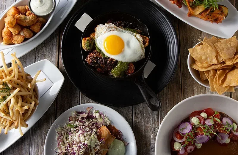 Overhead view of a diverse food spread on a rustic wooden table.