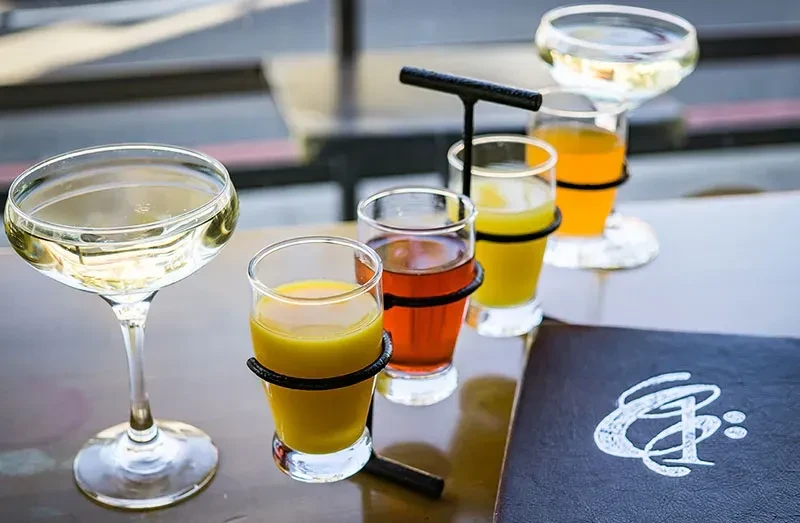 Drinks flight with colorful beverages and a champagne coupe.
