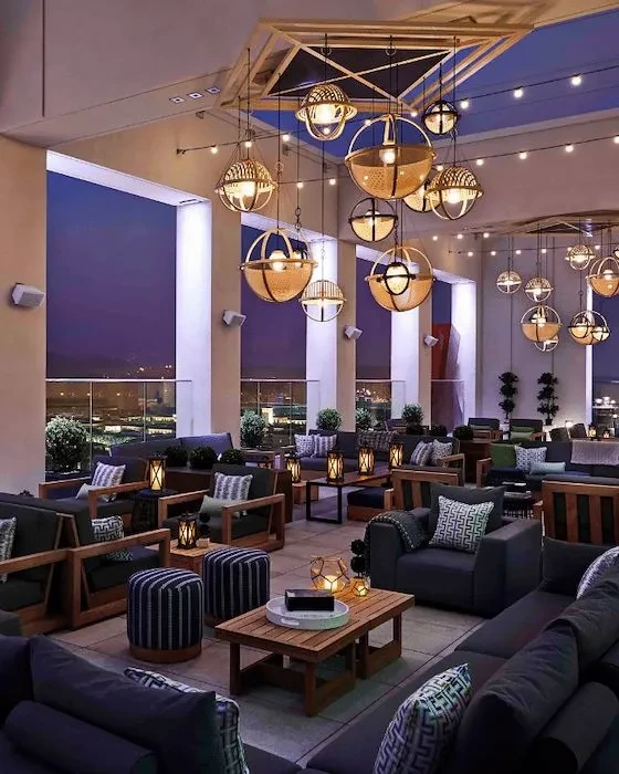 Elegant outdoor lounge with warm lighting and city skyline at night.