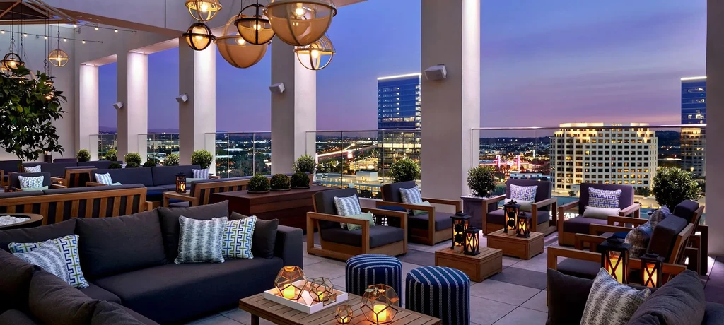 Empty modern rooftop lounge at dusk with a panoramic city skyline view.