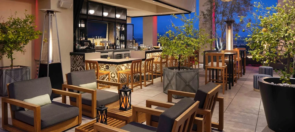Elevated outdoor bar and lounge with warm lighting at dusk.