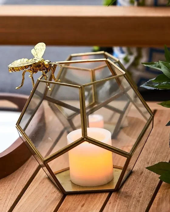Brass-framed glass lantern with LED candle and a golden bee figurine.