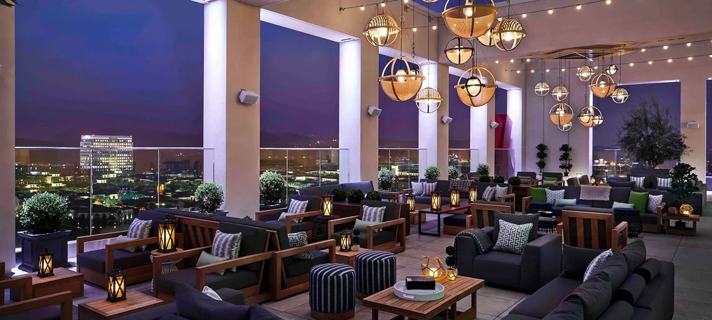 Empty rooftop lounge with comfortable seating overlooking city skyline at night.