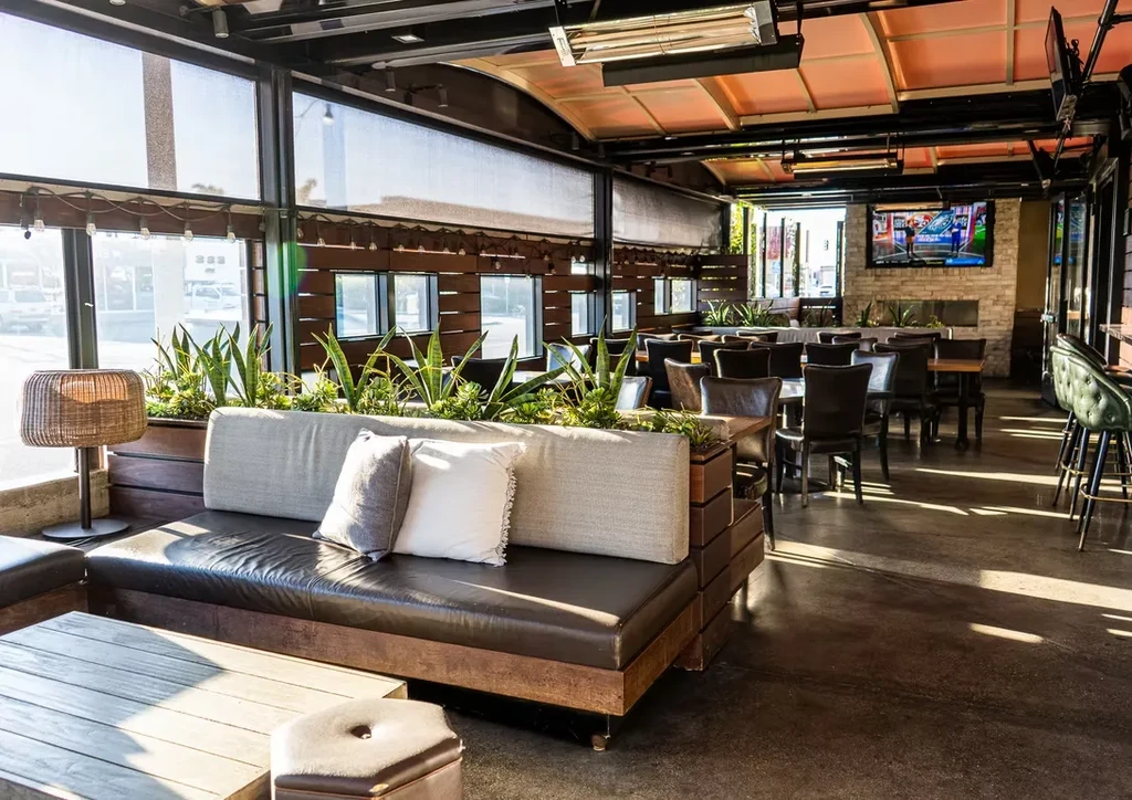 Modern indoor-outdoor restaurant with lounge, dining, bar, and large windows.