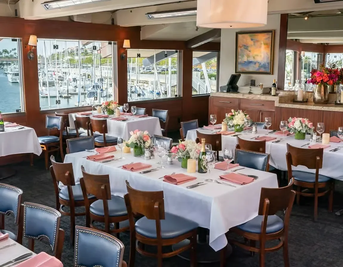Dining room with white linen tables and harbor marina window views