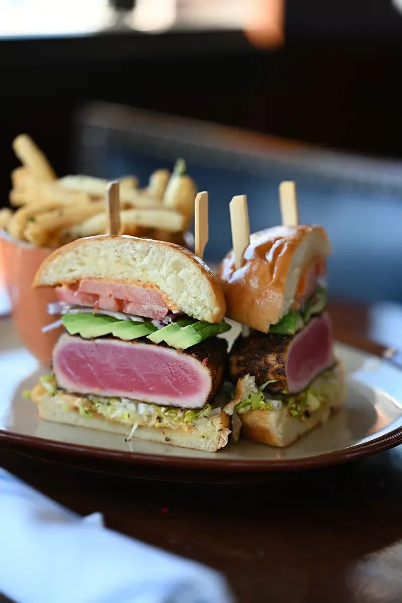 Seared ahi tuna sandwich halves with avocado and a side of fries