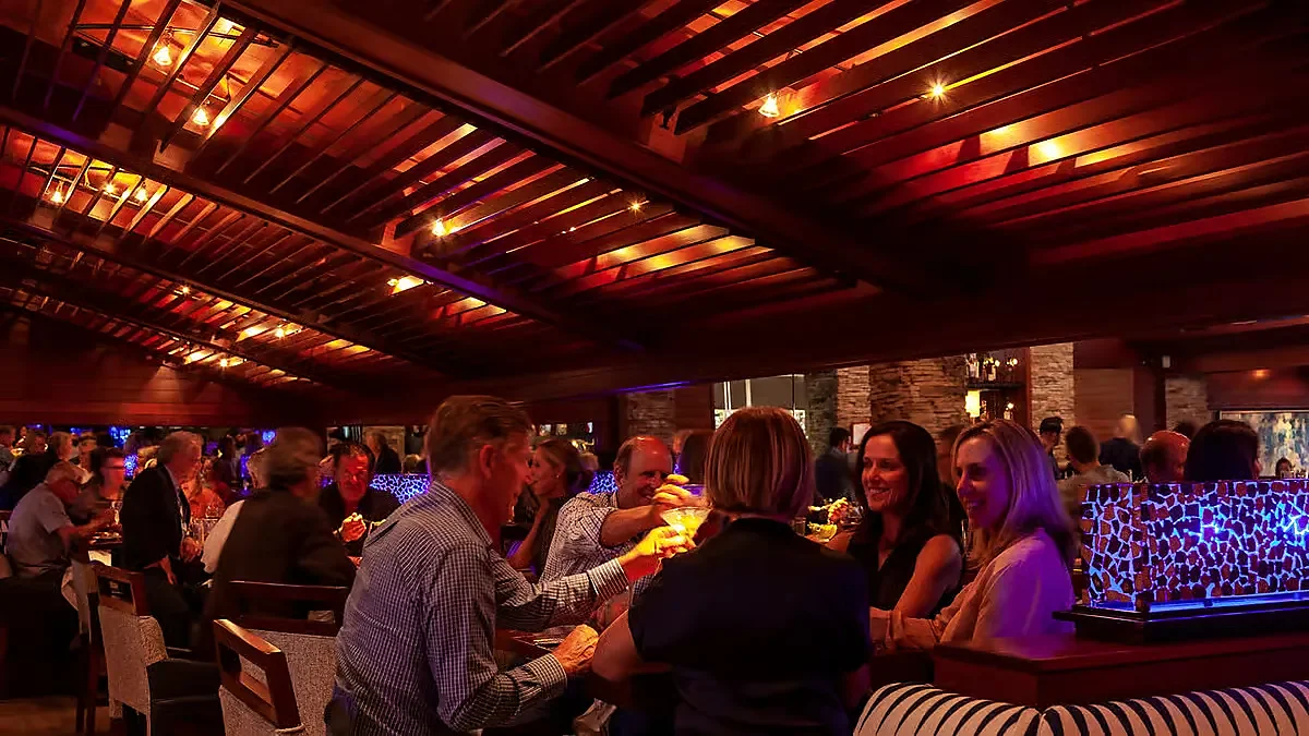 Guests seated at the bar under a warmly lit wood beam ceiling