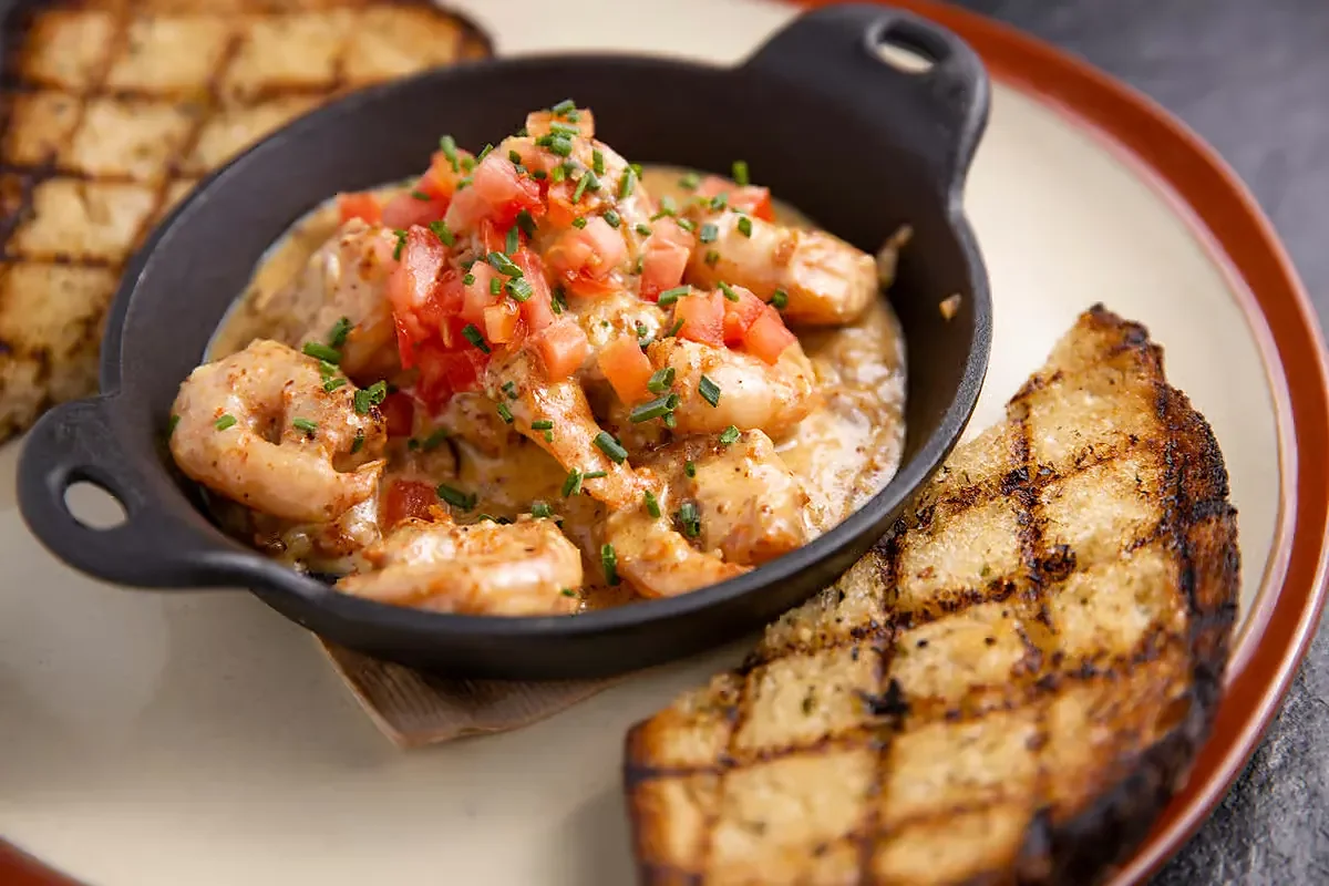 Shrimp in cream sauce with tomatoes in skillet with grilled bread