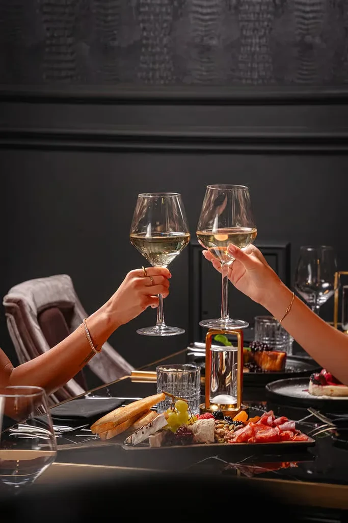 Hands toasting wine glasses over a charcuterie board in an upscale restaurant.