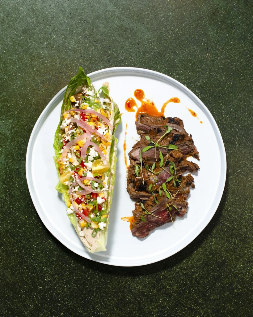 Grilled steak and romaine lettuce with colorful toppings, professionally plated.