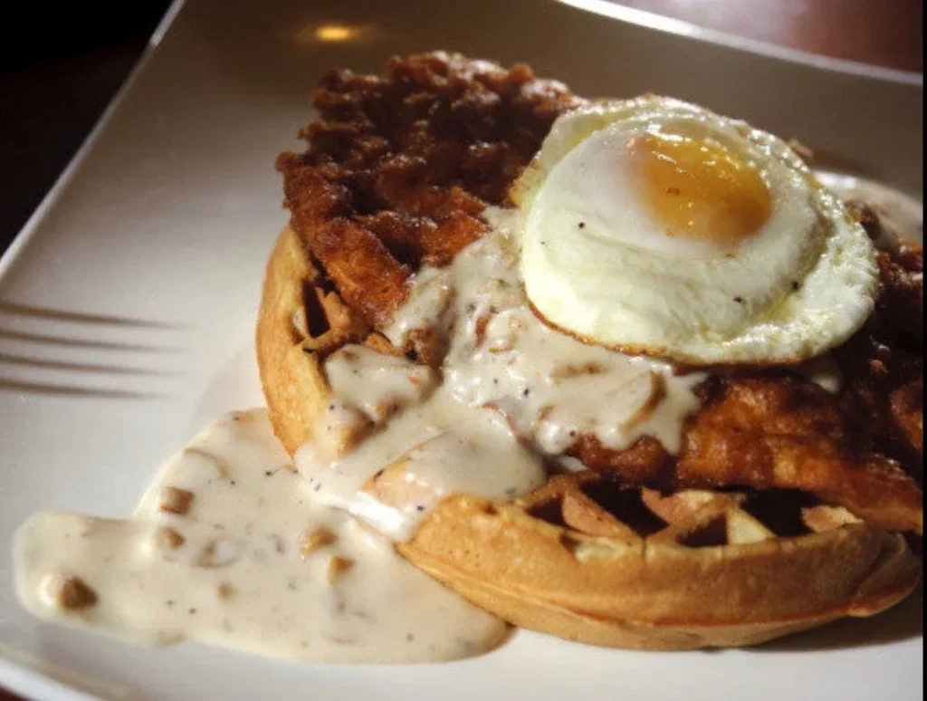 Waffle with crispy fried chicken, gravy, and a sunny-side-up egg.
