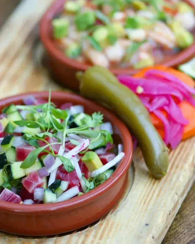 Colorful tuna and shrimp poke bowls with chili and pickled onions.