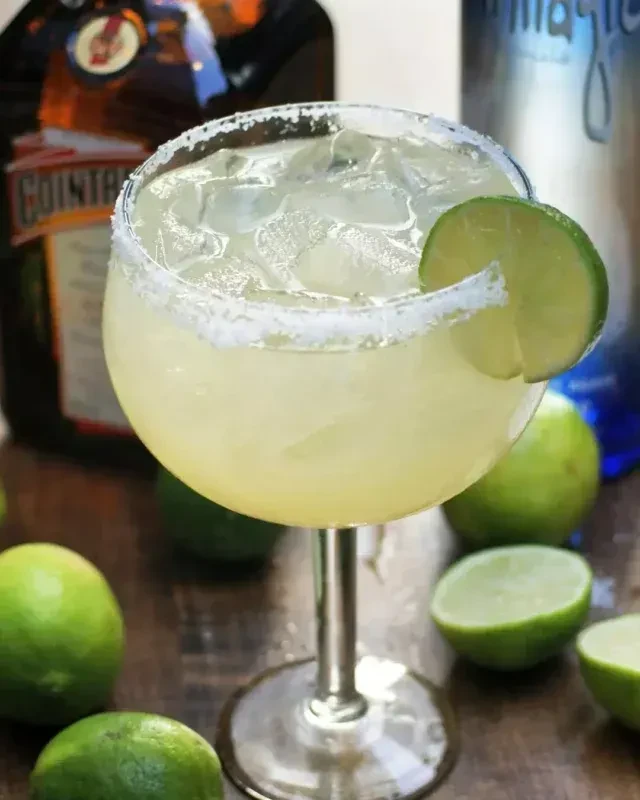 Pale green margarita with salted rim and lime garnish.