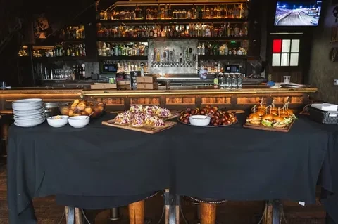 Appetizer buffet with mini burgers and tacos at a rustic bar.