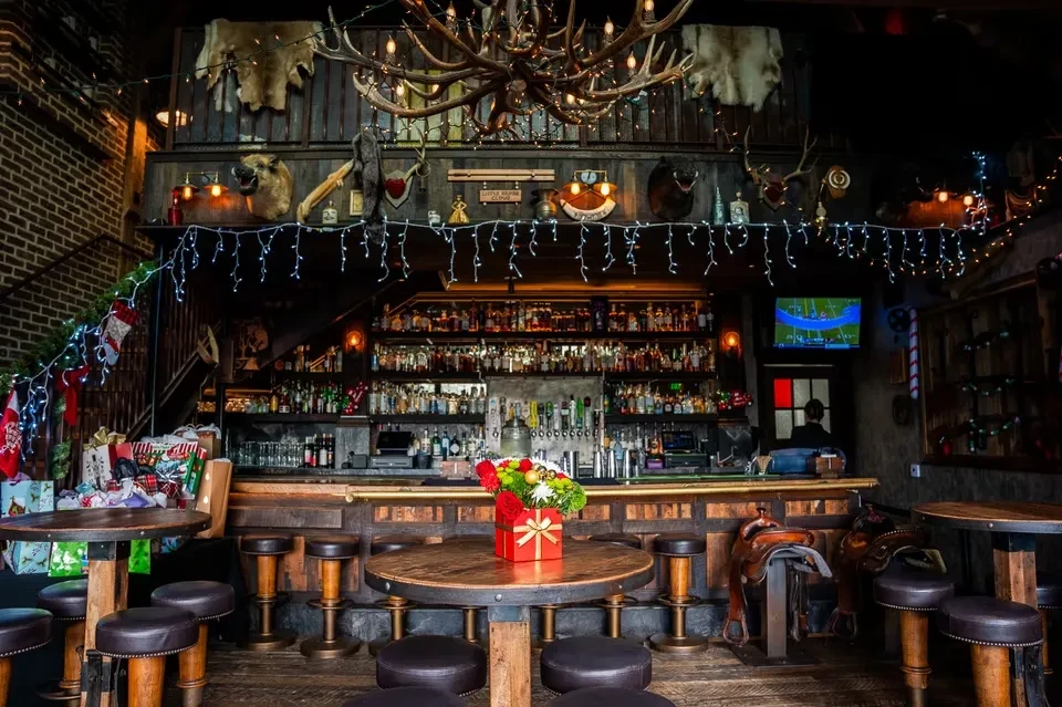 Rustic bar interior decorated for Christmas with antlers and fairy lights.