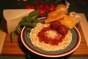 Rustic still life of spaghetti and meatballs with fresh ingredients.