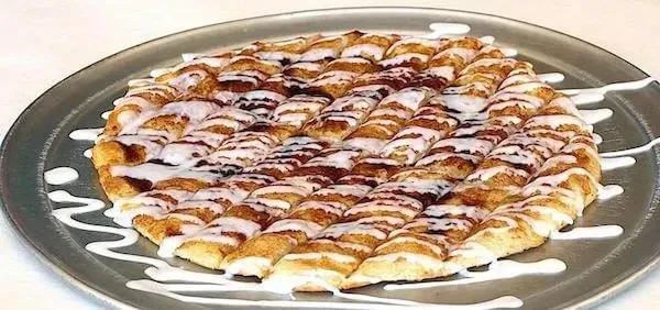 Golden-brown cinnamon pull-apart bread, drizzled with white icing on a tray.