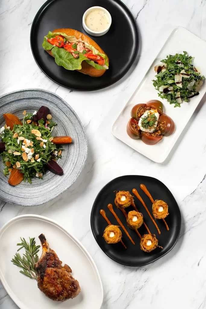 Overhead view of five artfully presented dishes on white marble.