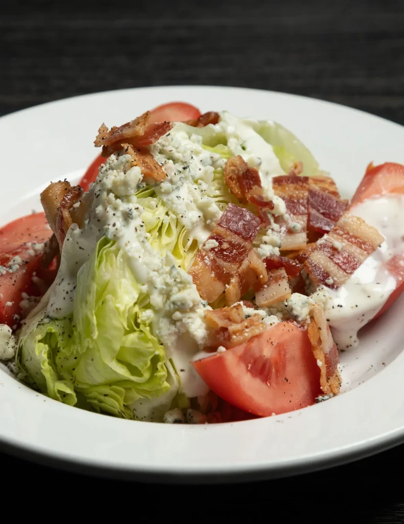 Close-up of a wedge salad with blue cheese, bacon, and tomato.