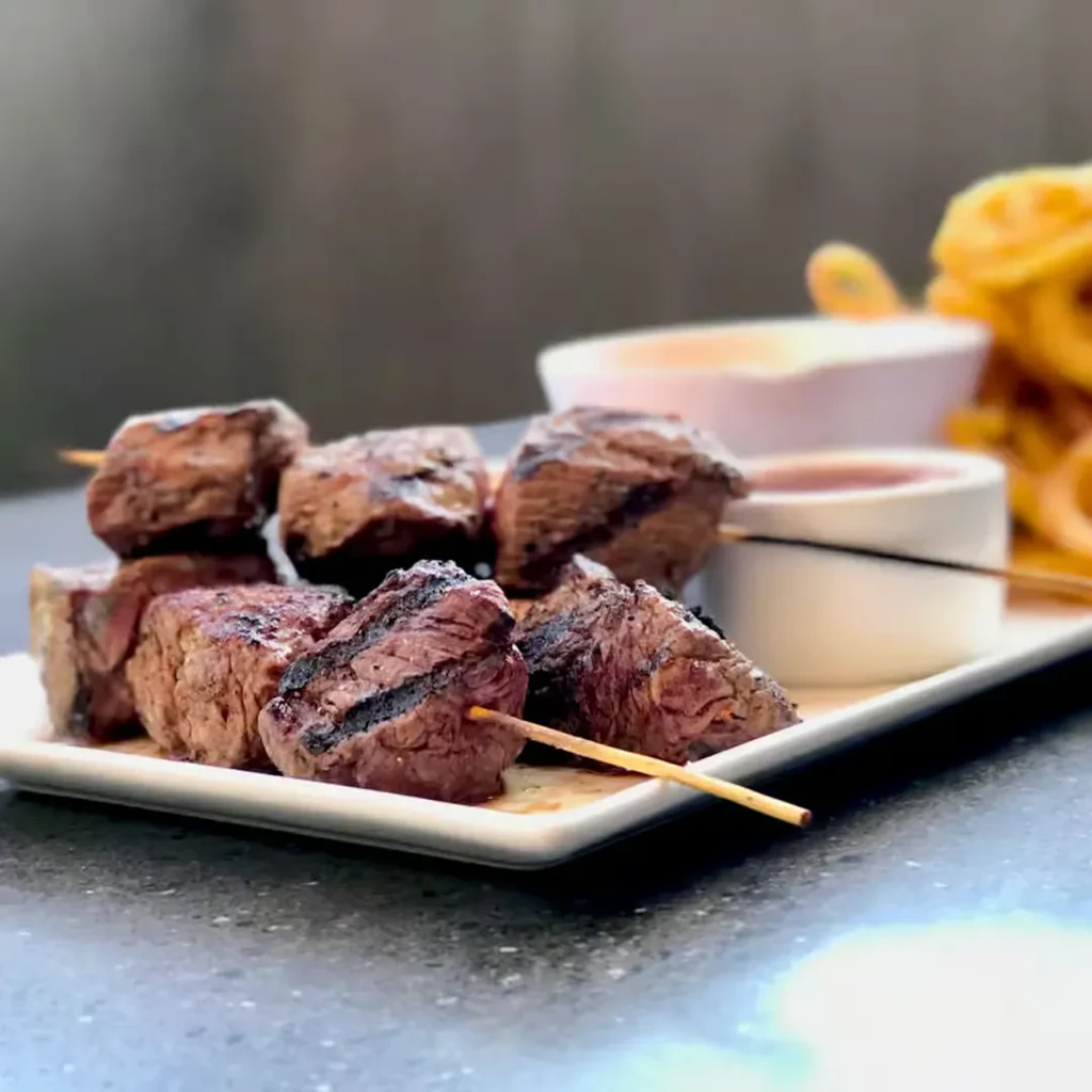 Grilled beef skewers with sauces and golden curly fries.