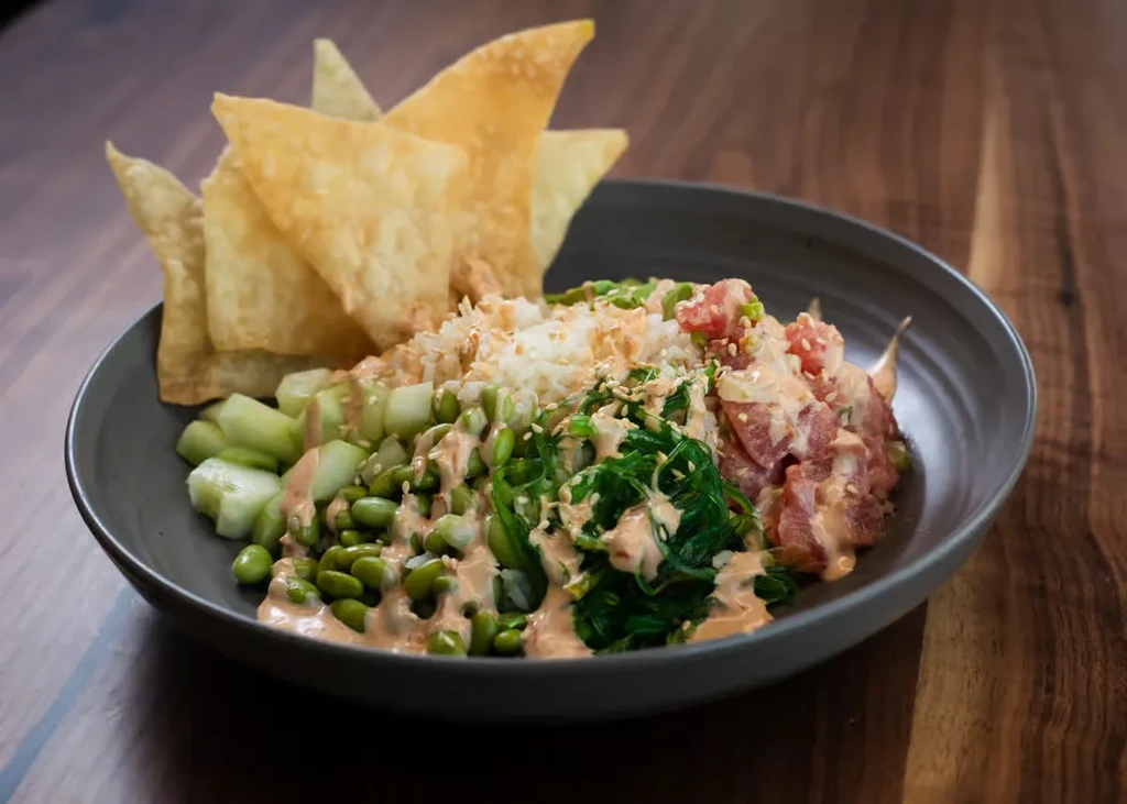 Vibrant poke bowl with marinated tuna, rice, veggies, and crispy chips.