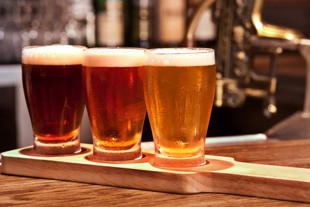 Cold beer flight with three distinct colors on a wooden paddle.