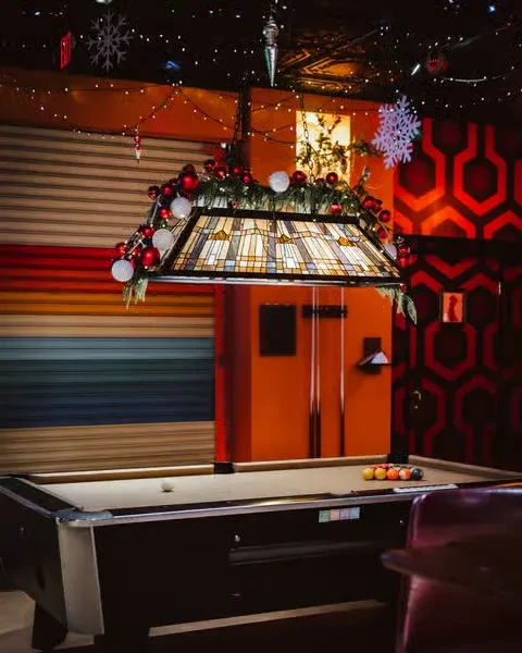 Festive bar interior with a pool table, holiday decorations, and colorful walls.