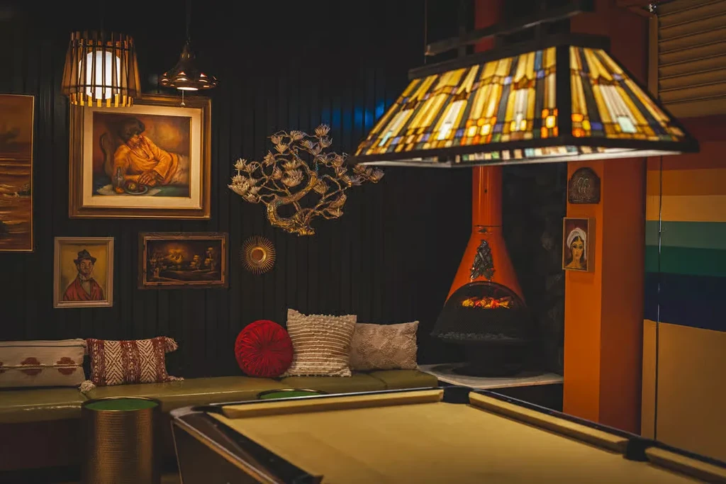 Eclectic interior with pool table, banquette, orange fireplace, and wall art.
