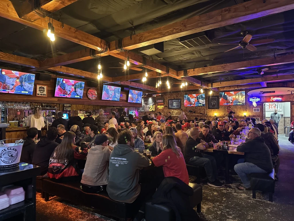 Lively sports bar with patrons watching football on multiple TVs.